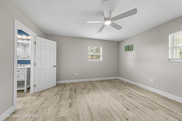 unfurnished bedroom with a textured ceiling, multiple windows, light hardwood / wood-style floors, and ceiling fan