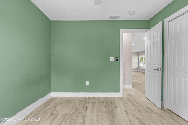 unfurnished room featuring a textured ceiling and light hardwood / wood-style flooring