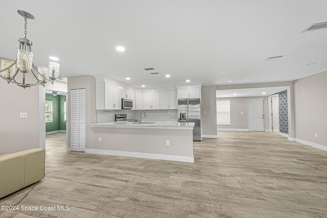 kitchen with stainless steel appliances, sink, decorative light fixtures, an inviting chandelier, and white cabinets