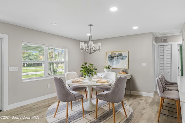 dining space with light hardwood / wood-style floors and an inviting chandelier