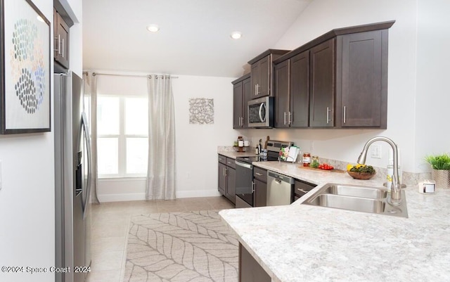 kitchen with stainless steel appliances, vaulted ceiling, light tile patterned floors, and sink