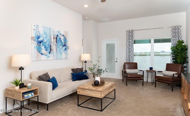 living room featuring light colored carpet and a water view