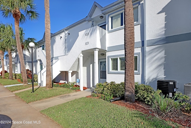 view of property with a front lawn and central AC unit