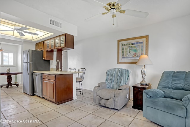 kitchen featuring sink, ceiling fan, light tile patterned floors, and stainless steel dishwasher