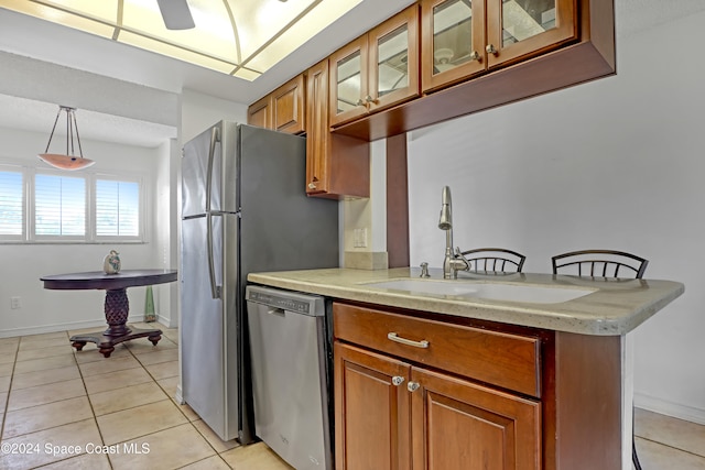 kitchen featuring stainless steel dishwasher, hanging light fixtures, sink, and light tile patterned floors