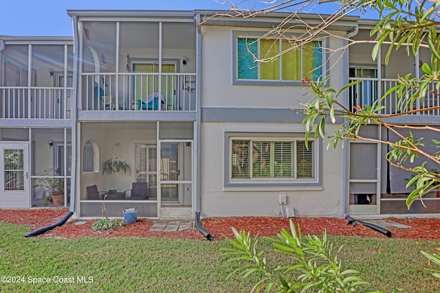 rear view of house featuring a balcony and a lawn