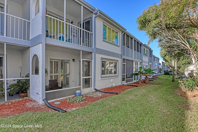 rear view of house with a yard and a balcony