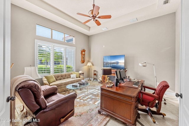 living room with ceiling fan, light tile patterned flooring, and a raised ceiling