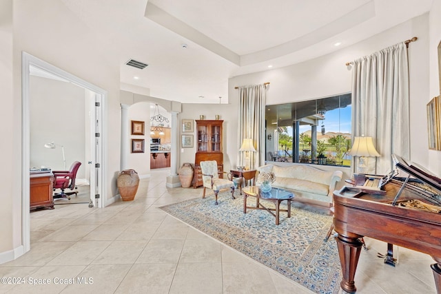 tiled living room featuring a raised ceiling and ornate columns