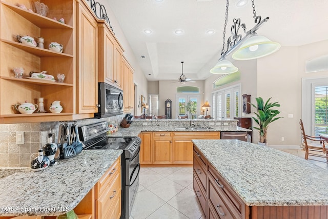 kitchen featuring light stone countertops, ceiling fan, sink, black appliances, and a kitchen island