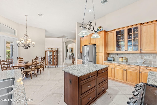 kitchen featuring a center island, stainless steel refrigerator with ice dispenser, hanging light fixtures, tasteful backsplash, and light stone counters