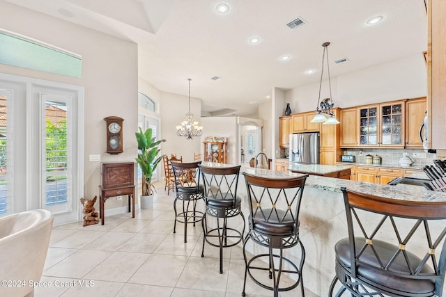 kitchen featuring hanging light fixtures, stainless steel fridge, tasteful backsplash, kitchen peninsula, and a breakfast bar area