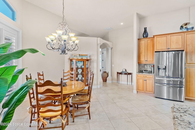 dining room featuring decorative columns, light tile patterned flooring, a high ceiling, and a notable chandelier