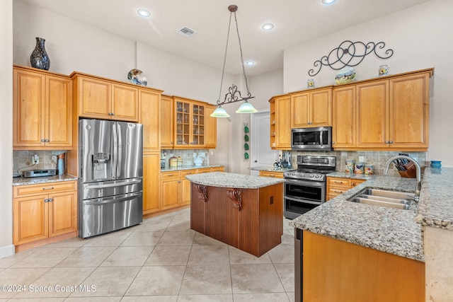 kitchen featuring light stone countertops, sink, stainless steel appliances, pendant lighting, and light tile patterned floors