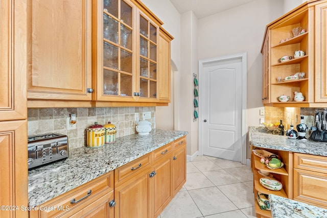 kitchen with tasteful backsplash, light stone counters, and light tile patterned flooring