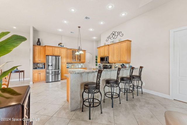 kitchen with hanging light fixtures, stainless steel appliances, tasteful backsplash, kitchen peninsula, and light tile patterned floors