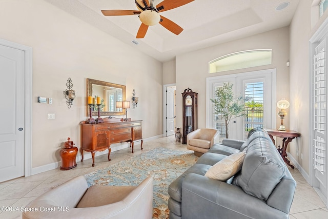 living room with ceiling fan, a raised ceiling, and light tile patterned floors