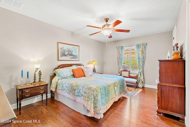 bedroom with wood-type flooring, a textured ceiling, and ceiling fan