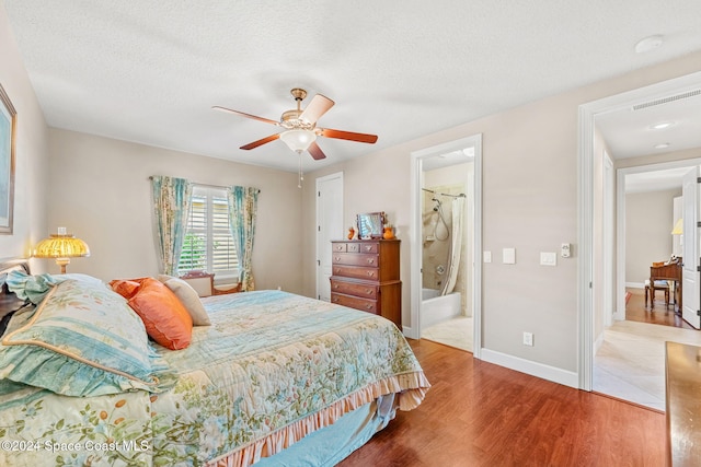 bedroom with a textured ceiling, connected bathroom, light hardwood / wood-style floors, and ceiling fan