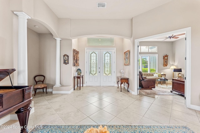 tiled foyer entrance featuring decorative columns, ceiling fan, and french doors