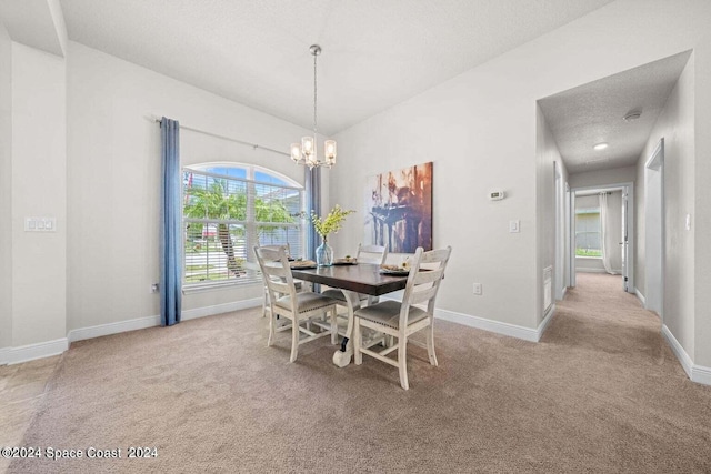 dining room with light colored carpet, a textured ceiling, and a notable chandelier