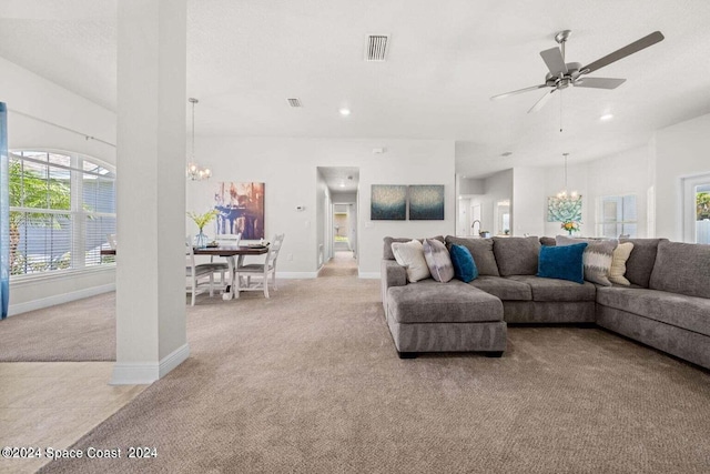 carpeted living room featuring ceiling fan with notable chandelier