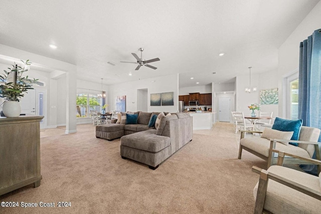 living room featuring light carpet and ceiling fan with notable chandelier