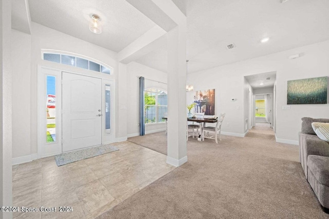 carpeted entryway featuring a notable chandelier and a textured ceiling