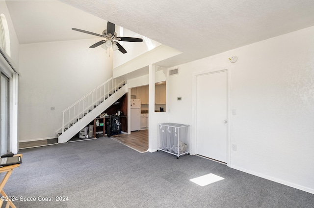 unfurnished living room featuring ceiling fan, a textured ceiling, dark carpet, and high vaulted ceiling