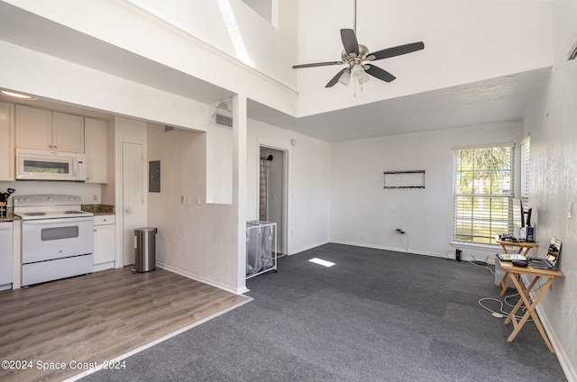 kitchen with ceiling fan, electric panel, white appliances, a high ceiling, and hardwood / wood-style floors