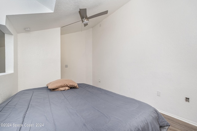 unfurnished bedroom with ceiling fan, a textured ceiling, and hardwood / wood-style floors