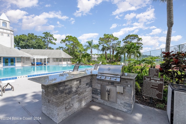 view of patio / terrace with an outdoor kitchen, grilling area, and a community pool