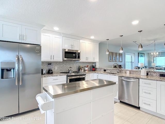 kitchen featuring stainless steel appliances, white cabinetry, kitchen peninsula, and decorative light fixtures