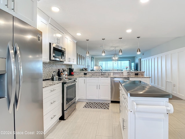 kitchen with stainless steel appliances, white cabinets, kitchen peninsula, and decorative light fixtures