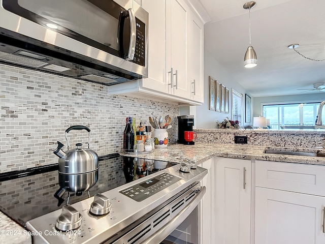 kitchen with white cabinets, sink, backsplash, stainless steel appliances, and light stone countertops