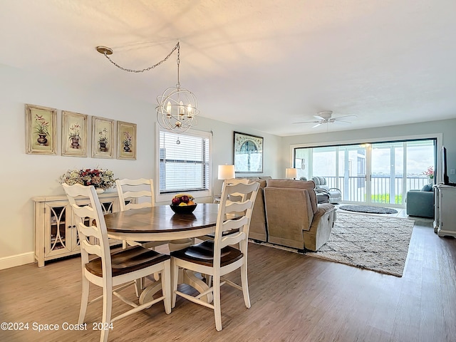 dining room featuring ceiling fan with notable chandelier and hardwood / wood-style floors