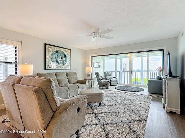 living room featuring ceiling fan, a textured ceiling, and light hardwood / wood-style flooring