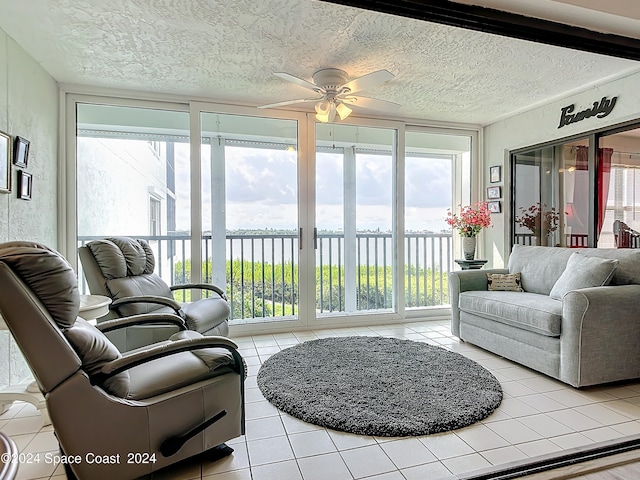 sunroom with ceiling fan and a water view