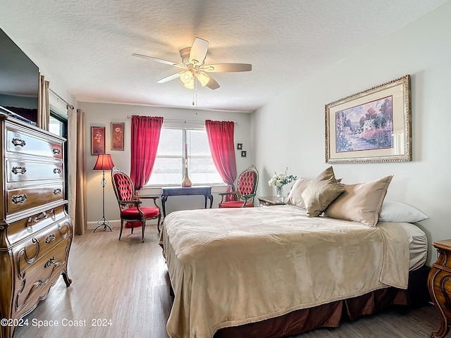 bedroom with ceiling fan, hardwood / wood-style flooring, and a textured ceiling