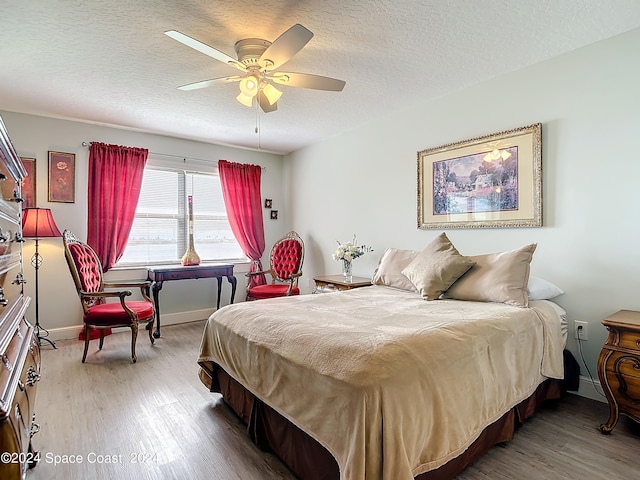 bedroom with ceiling fan, hardwood / wood-style floors, and a textured ceiling