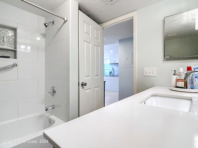 bathroom with vanity, a textured ceiling, and tiled shower / bath