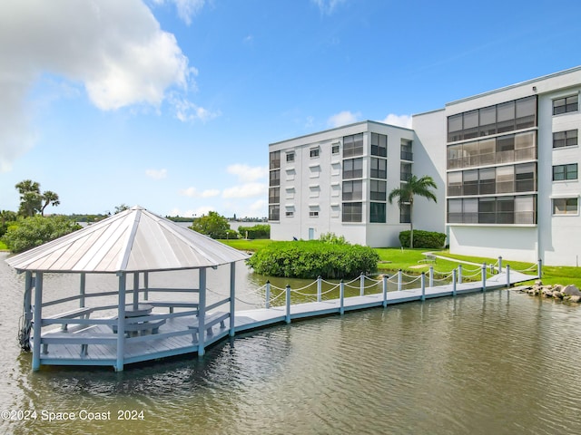 view of dock featuring a gazebo, a lawn, and a water view