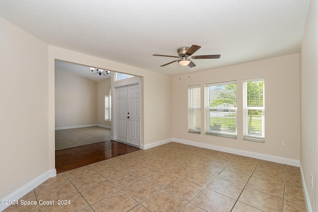 tiled empty room featuring ceiling fan and a textured ceiling