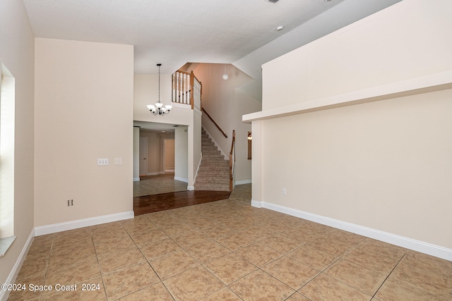 unfurnished room with an inviting chandelier, tile patterned flooring, and high vaulted ceiling