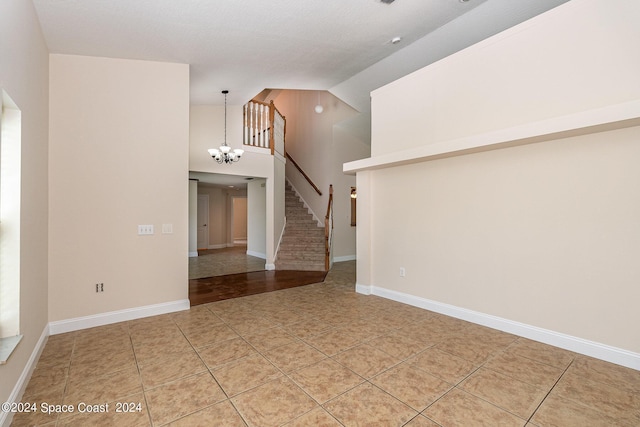 1290 Mercedes Dr, Merritt Island, FL 32952 - empty room featuring high vaulted ceiling, light tile patterned flooring, a chandelier, stairs, and baseboards