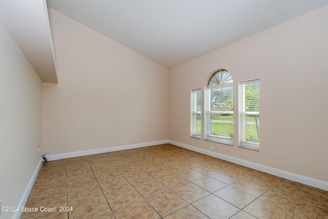 spare room with light tile patterned flooring and vaulted ceiling