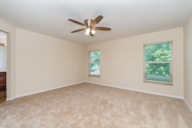 empty room with a textured ceiling, ceiling fan, and light colored carpet