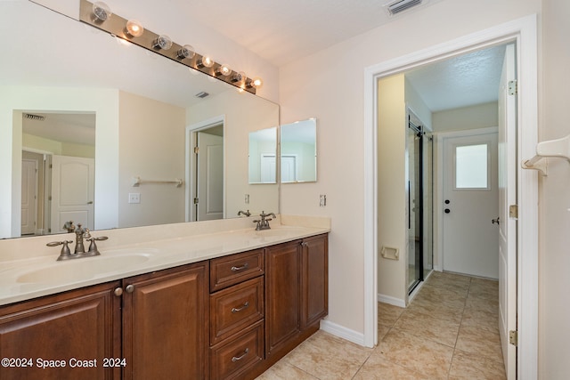 bathroom with tile patterned flooring, a shower with door, and vanity