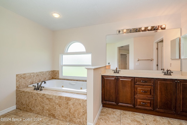 bathroom with tiled bath, vanity, and tile patterned flooring