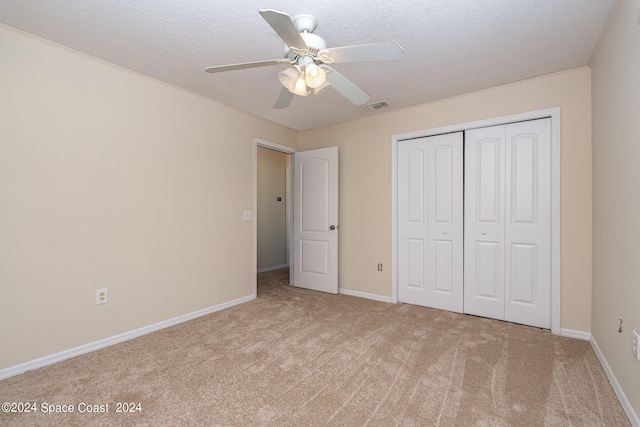 unfurnished bedroom with a textured ceiling, carpet, ceiling fan, and a closet